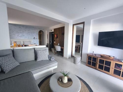 Una sala de estar con un sofá y un televisor. en EXO Santorini Sea View Private Pool Villa and Suites, en Éxo Goniá