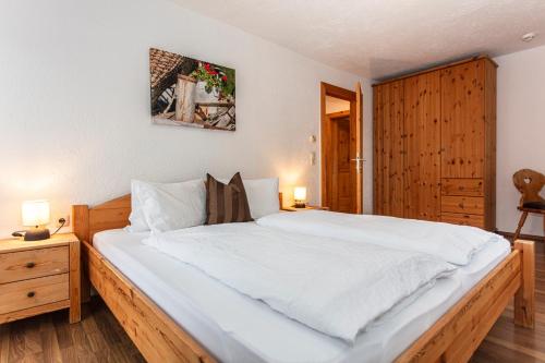 a bedroom with a large white bed and a wooden cabinet at Gästehaus Dreier in Neukirchen am Großvenediger