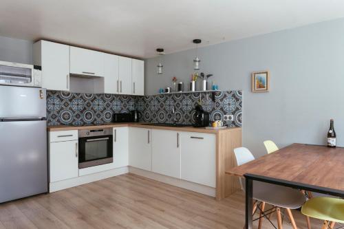 Una cocina con gabinetes blancos y una mesa de madera. en Appartement duplex centre historique d'Auray, en Auray