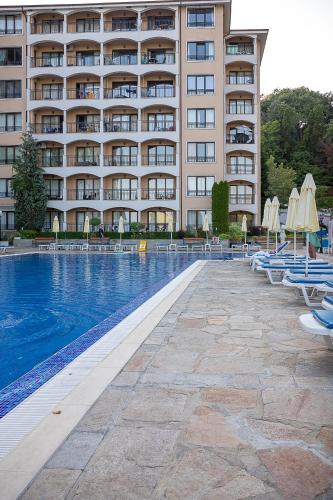 a hotel with a swimming pool with chairs and a building at Bendita Mare Aparthotel in Golden Sands