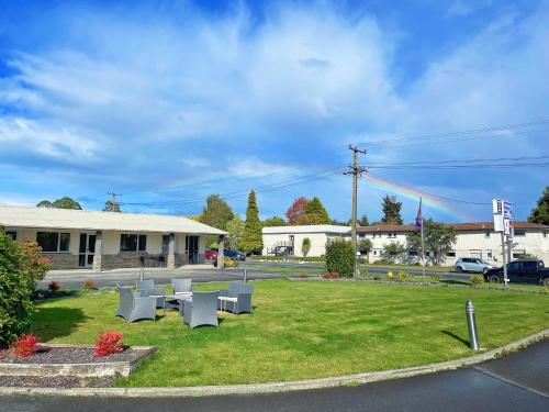 a yard with tables and chairs in front of a building at Anchorage Motel Apartments in Te Anau
