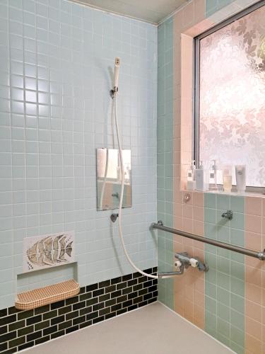 a shower in a bathroom with blue tiles at 登山外遊び仮眠所 みみずの寝床 mimizu no nedoko Overnight rest space in Matsumoto