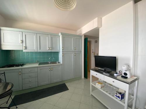 a kitchen with white cabinets and a flat screen tv at CannetoMare in Canneto