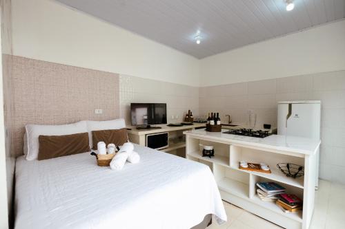 a white bedroom with a white bed and a kitchen at Estúdio privativo para hóspedes in São Roque