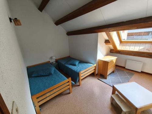 Cette chambre mansardée comprend 2 lits et une table. dans l'établissement Six Duplex à la montagne POMPIERY, à Seyne