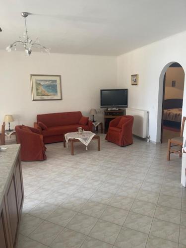 a living room with red couches and a tv at MOURTERI TASOSEVa in Mourteri