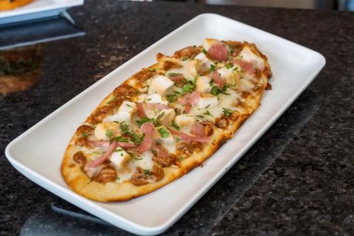 a pizza on a white plate on a table at Staybridge Suites Everett - Paine Field by IHG in Mukilteo