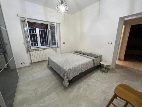 a white bedroom with a bed and a window at CasaDiFlavio in Torvaianica