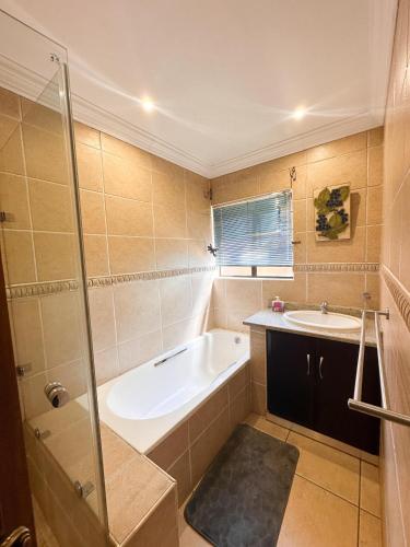 a bathroom with a bath tub and a sink at Tsheryl's Guesthouse in Centurion