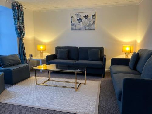a living room with blue couches and a coffee table at Etruria House - Near Water World, Festival Park and Bet365 in Stoke on Trent