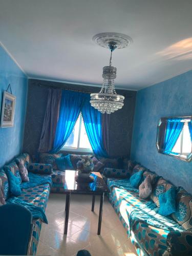 a blue living room with couches and a chandelier at Coastal Elegance in Martil