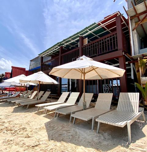 a row of beach chairs with umbrellas on the beach at Brisas del Mar Barú in Playa Blanca