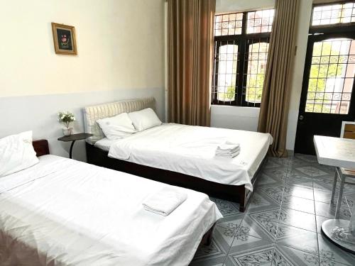 two beds in a room with white sheets at Hoe Stay - Where to stay in Hanoi