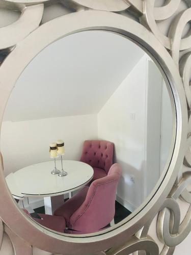 a mirror with a table and purple chairs in a room at Apartman Maslina in Kosjerić