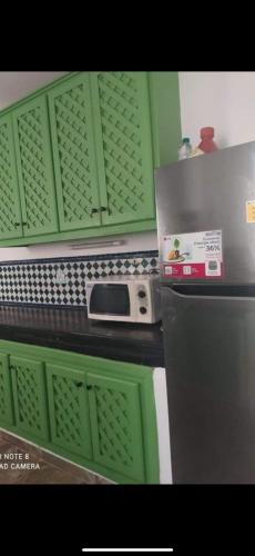 a kitchen with green cabinets and a refrigerator at Green house in Sidi Yahia az Zaʼer