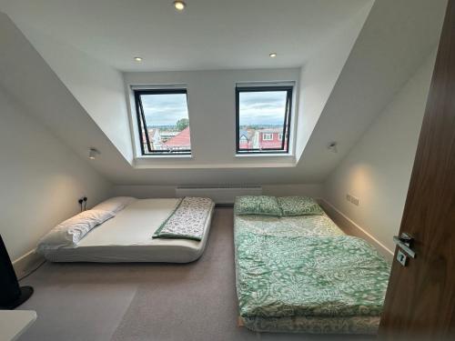 a attic bedroom with two beds and two windows at Kilby close in Edgware