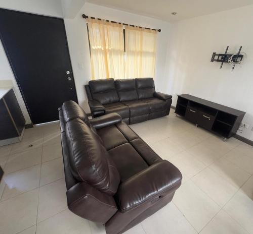 a living room with a leather couch and a television at House in Álika Club Residencial in Fraijanes