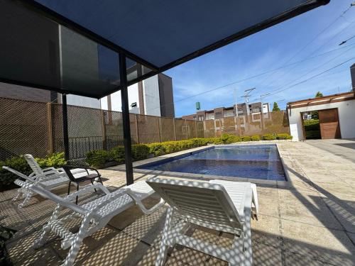 a patio with two white chairs and a swimming pool at House in Álika Club Residencial in Fraijanes