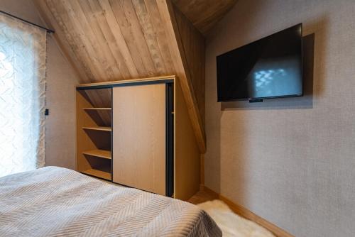 a bedroom with a bed and a flat screen tv on the wall at Ośrodek Wypoczynkowy Bernadetta in Murzasichle