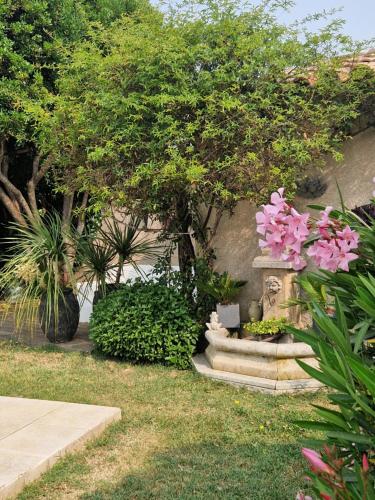 a garden with pink flowers and a stone fountain at La Parenthèse in Lauris