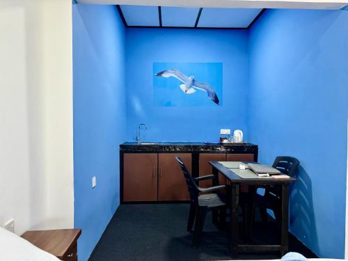 a blue room with a table and a bird flying overhead at Sea Breeze Stay in Negombo
