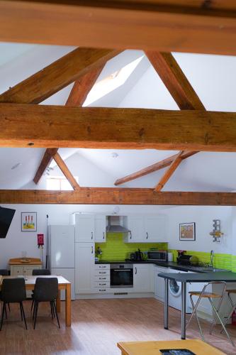 a kitchen with wooden ceilings and a table and chairs at The Courtyard at Lodge Farm in Norwich