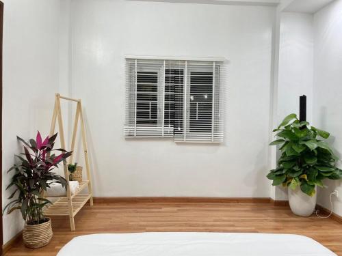une chambre blanche avec des plantes et une fenêtre dans l'établissement The Little Ha Noi 5 Bedrooms Large Yard Balcony, à Hanoï