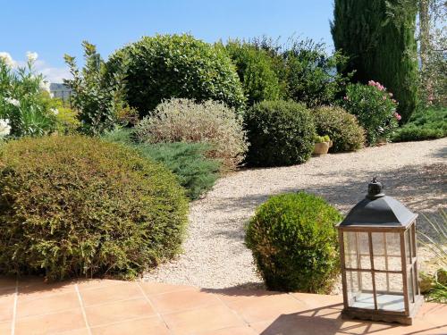 a lantern in a garden with bushes and a pathway at La Parenthèse in Lauris
