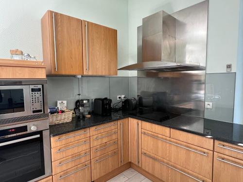 a kitchen with stainless steel appliances and wooden cabinets at Appartement de luxe plein centre in Divonne-les-Bains