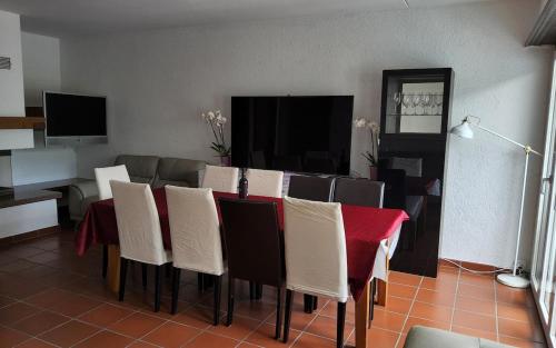 a dining room with a table with chairs and a television at ruhiges Haus am See in Agno in Agno