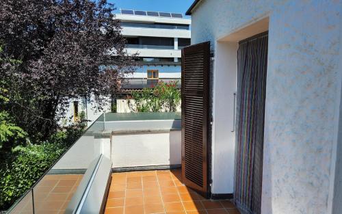 a balcony with an open door on a building at ruhiges Haus am See in Agno in Agno