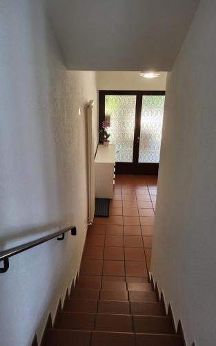 a hallway with stairs leading to a window and a door at ruhiges Haus am See in Agno in Agno