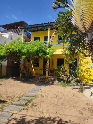 a yellow house with a palm tree in front of it at Capitólio 01 hospedagem Rua nascer do sol 03 Canoa Quebrada in Aracati