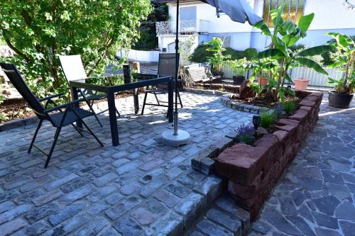 a patio with a table and a chair and an umbrella at Ferienwohnung Südwestpfälzer Ruheoase in Busenberg
