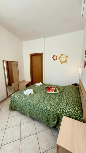 a bedroom with a bed with a green comforter at Ibisco Hotel in Rodi Garganico