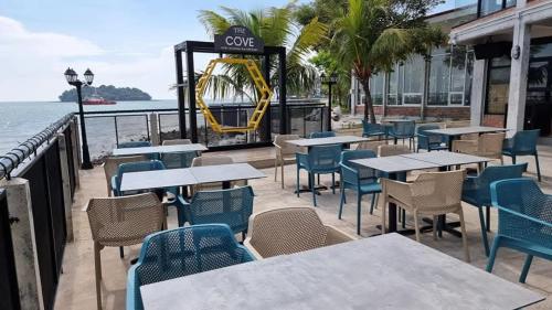 a restaurant with tables and chairs next to the water at PD Dwharf The Bay Oceanview Suite in Port Dickson