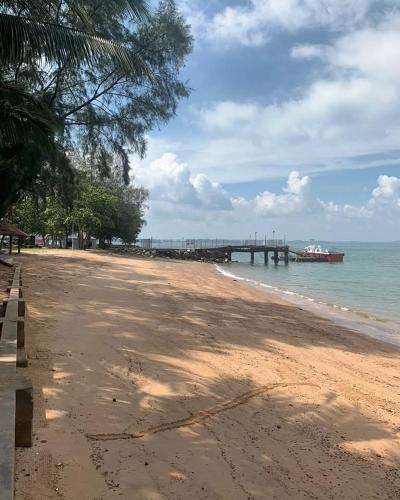 a beach with a pier and a boat in the water at PD Dwharf The Bay Oceanview Suite in Port Dickson