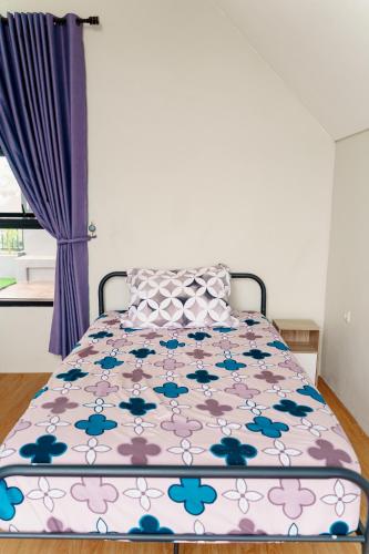 a bed in a bedroom with a purple curtain at Griya Saka Magelang in Magelang