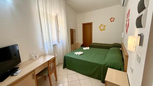 a small room with a green bed and a television at Ibisco Hotel in Rodi Garganico