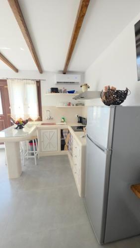 a white kitchen with a refrigerator and a table at Siroccos Apartment in Vlychádia