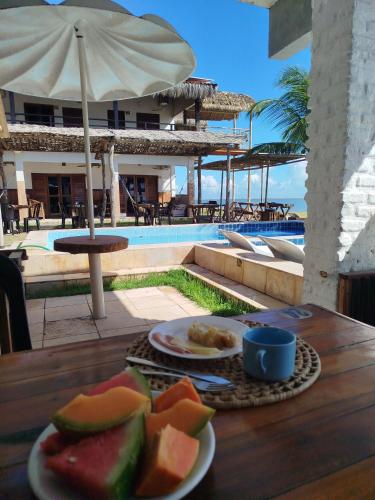 a table with plates of fruit on a table near a pool at Toca da Ilha in Itarema