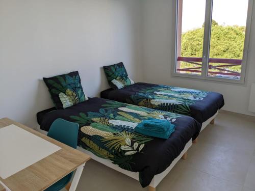 two beds in a room with a table and window at Cocon moderne avec terrasse a deux pas de locean in Saint-Brevin-les-Pins