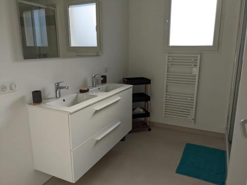 a white bathroom with a sink and a mirror at Cocon moderne avec terrasse a deux pas de locean in Saint-Brevin-les-Pins