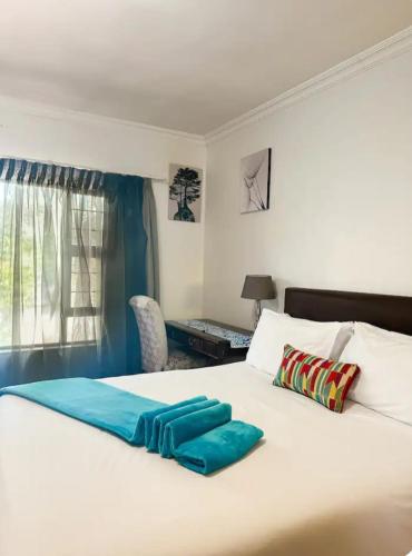 a bedroom with a large white bed with blue sheets at Tsheryl's Guesthouse in Centurion