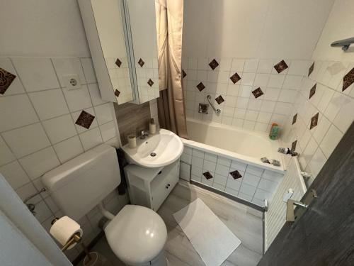 a bathroom with a sink and a toilet and a tub at Boho Apartment Birkenstöckl in Bad Reichenhall