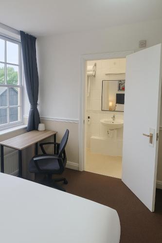 a room with a desk and a chair and a bathroom at The Swan Hotel Oxford in Eynsham