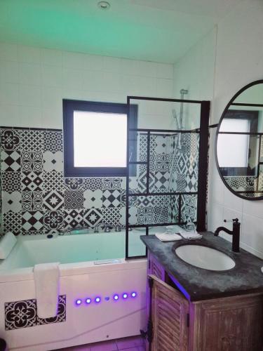a bathroom with a sink and a tub and a mirror at Hôtel Des Argousiers in Ambleteuse