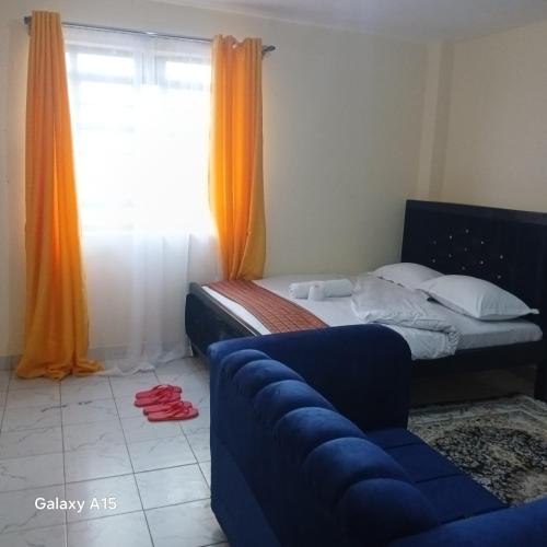 a bedroom with a bed and a couch and a window at Dhahabu homes in Kitengela 