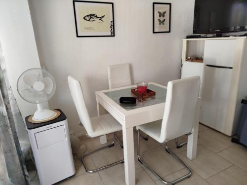 Una mesa y sillas blancas con un ventilador y un refrigerador. en Appartement La Casa Verde, en Llançà