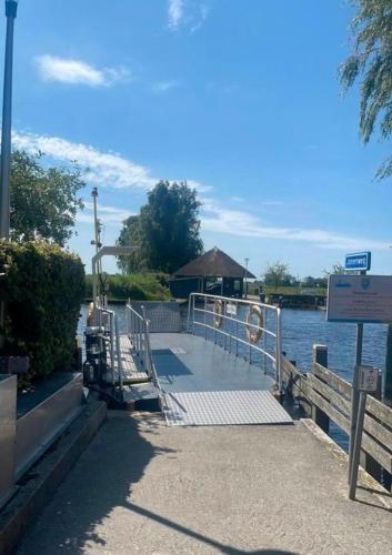 a dock with a sign next to the water at Achterhuis Echt mooi in Nijeveen